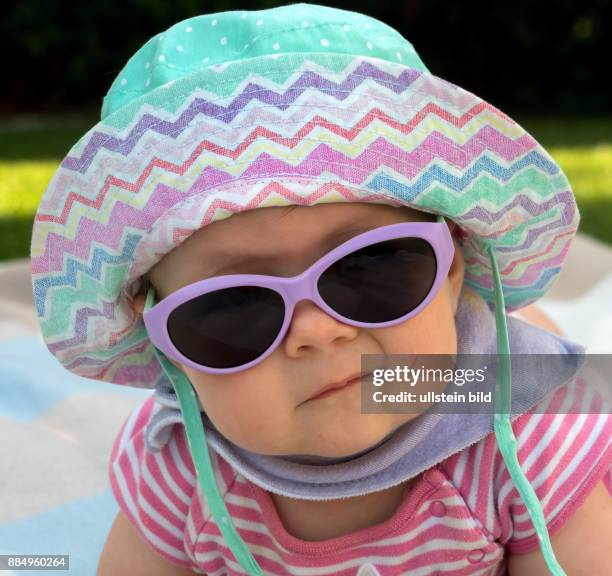 Ein Baby mit Sonnenbrille und Sonnenhut ist gut gegen die Hitze im Sommer ausgestattet