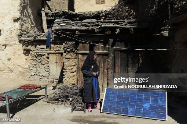 In this photograph taken on October 25, 2017 Afghan widow Janat Bibi stands outside her mud house in the remote village of Shemol in the eastern...