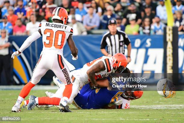 Hunter Henry of the Los Angeles Chargers loses his helmet after being tackled by Joe Schobert and Christian Kirksey of the Cleveland Browns during...