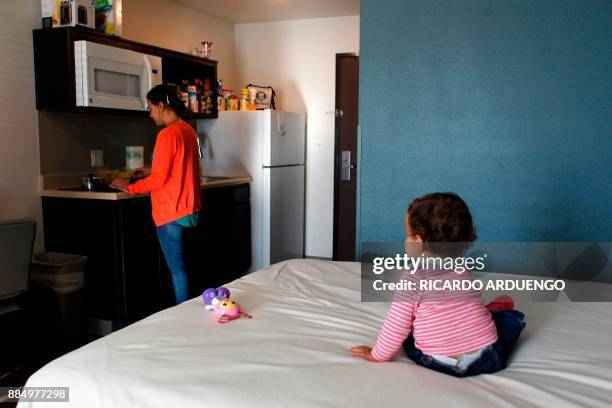 Genesis Rivera, 10mo, watches her mother Deborah Oquendo prepare breakfast at the hotel were they are staying in Orlando, Florida on December 1,...