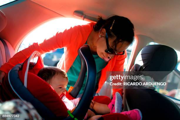 Deborah Oquendo removes from her car her 10mo old daughter Genesis Rivera in her carseat in Orlando, Florida on December 1, 2017. On September 20...