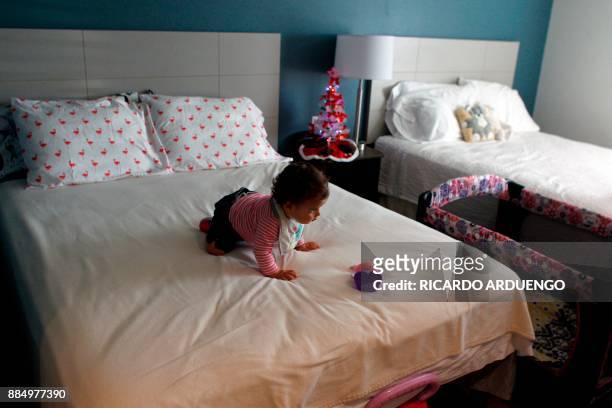 Genesis Rivera, 10mo, plays on a hotel bed where she and her mother Deborah Oquendo are staying in Orlando, Florida on December 1, 2017. On September...