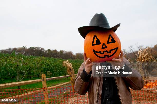 man holding up a jack o'lantern pumpkin as his face. - marie hickman all images stock pictures, royalty-free photos & images