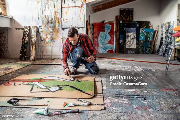 artist painting canvas cardboard on floor - artist imagens e fotografias de stock