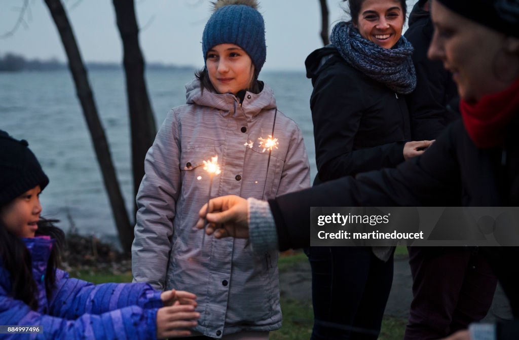 Friends and family celebrating winter with sparklers outdoors at dusk