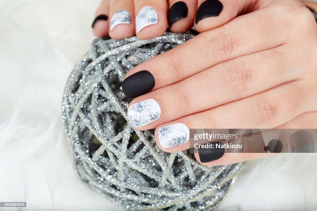 Mãos com unhas feitas, coloridas com esmalte preto e branco