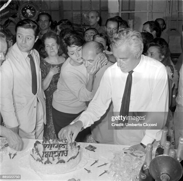 Sophia Loren hugs film producer Carlo Ponti during her twenty-ninth birthday party, Marcello Mastroianni and Vittorio De Sica are attending the party...