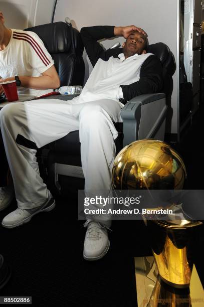 Los Angeles Lakers' Kobe Bryant relaxes next to the Larry O'Brien Trophy during the Lakers flight back to Los Angeles on June 15, 2009 in Los...