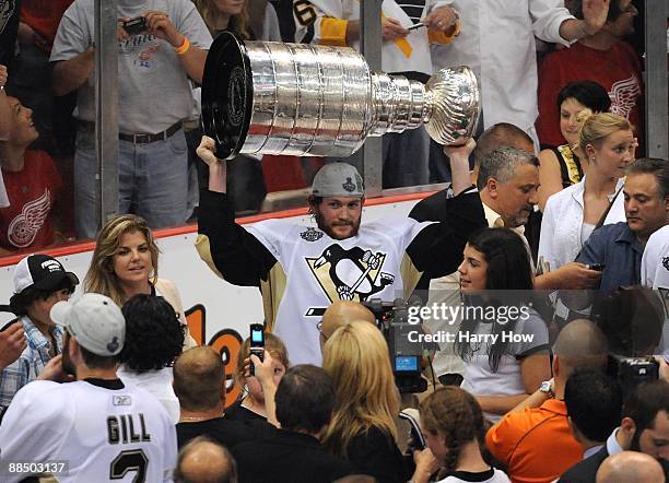Matt Cooke of the Pittsburgh Penguins hoists the Stanley Cup overhead after Game Seven of the 2009 NHL Stanley Cup Finals against the Detroit Red...