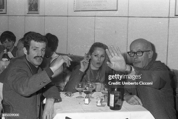 Film actress Ursula Andress and French actor Jean-Paul Belmondo with a friend at the restaurant , Rome 1966.