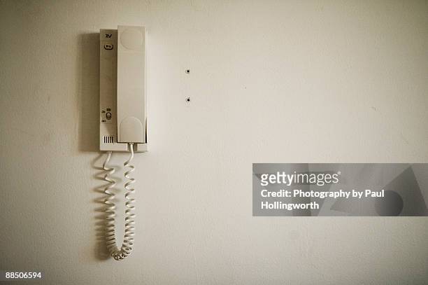 intercom handset hanging on a cream wall. - citofono foto e immagini stock