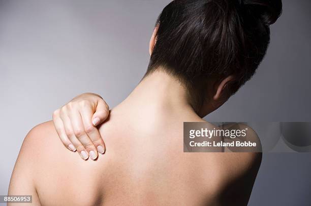 woman with back pain massaging shoulder - back pain 個照片及圖片檔