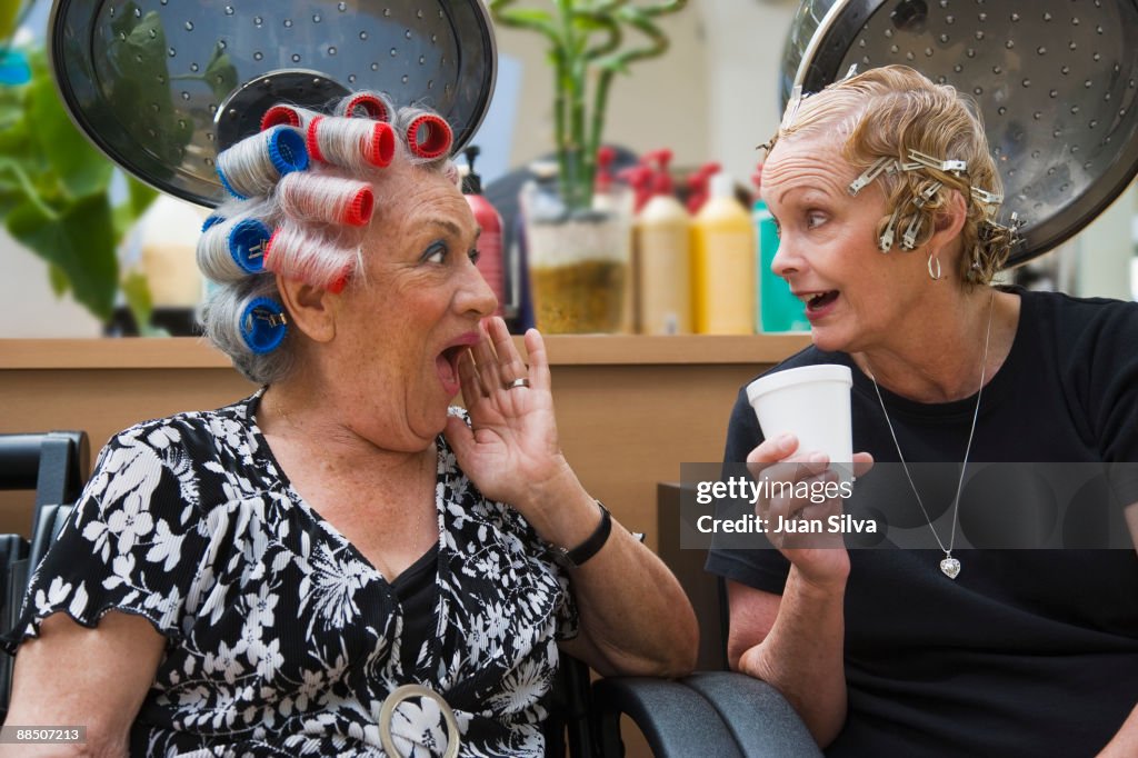 Two older woman gossiping at hair salon