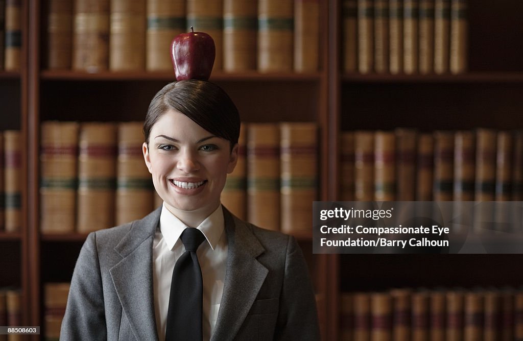 Woman in suit balancing red apple on head