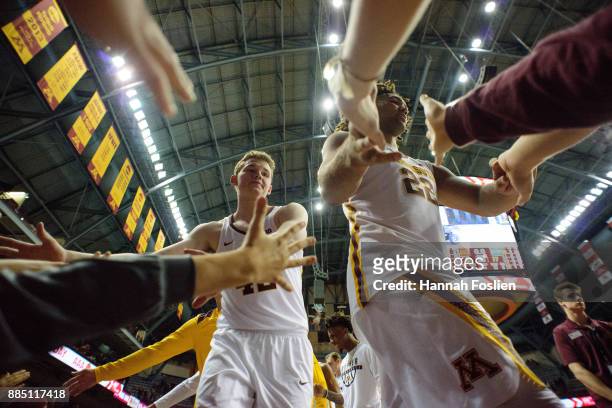 Michael Hurt and Reggie Lynch of the Minnesota Golden Gophers celebrate a win against the USC Upstate Spartans with fans after the game on November...