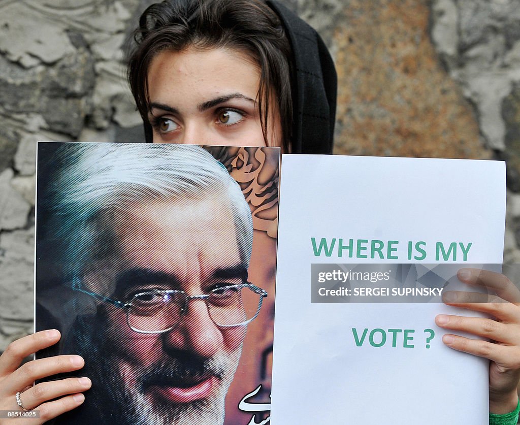 A young Iranian woman holds a placard an