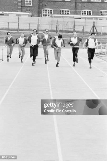 Group portrait of Dexys Midnight Runners with Kevin Rowland running at an athletics track in Birmingham, England in July 1981.