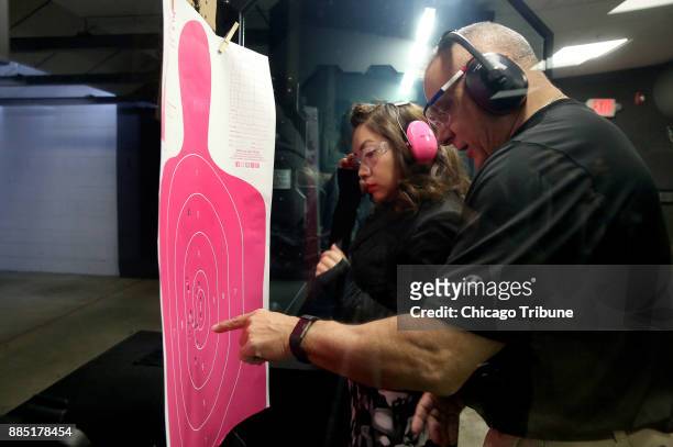 Shooting instructor Tony Wasco goes over Sonia Figueroa's target with her on Sunday, Nov. 12, 2017 at the Eagle Sports Range in Oak Forest, Ill....