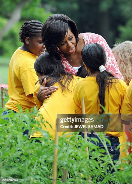 First Lady Michelle Obama hugs a fifth grade student as they harvest in the White House Kitchen Garden at the White House in Washington, DC, on June...