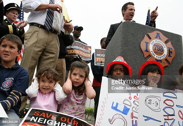 Two young girls cover their ears as San Francisco mayor Gavin Newsom speaks during a rally against cutting funding to San Francisco public safety...