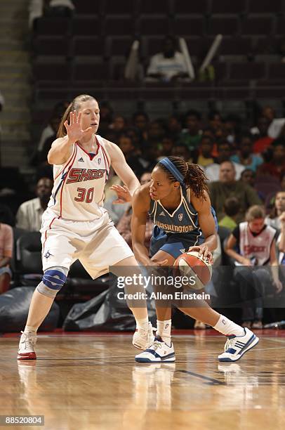 Monique Currie of the Washington Mystics moves the ball against Katie Smith of the Detroit Shock during the game on June 10, 2009 at The Palace of...