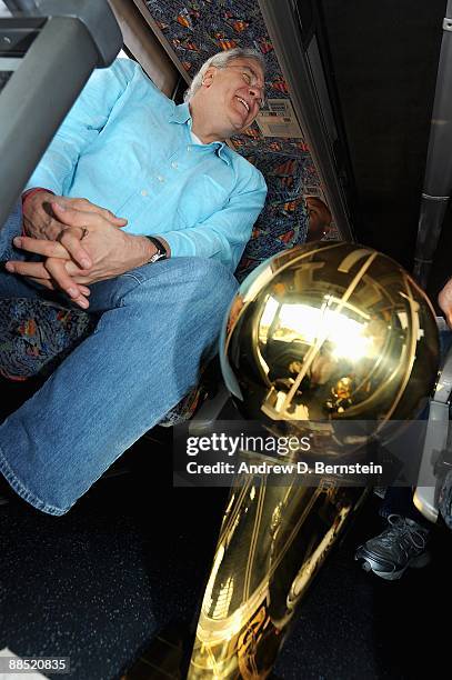 Head coach Phil Jackson of the Los Angeles Lakers smiles on the way to the airport as the Larry O'Brien trophy sits on the ground next to him on June...