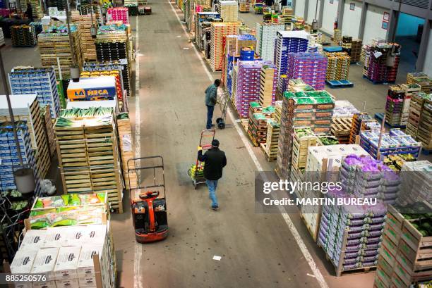 Man pushes a trolley at the vegetable area of the international food market of Rungis, on December 1, 2017 in Rungis, outside Paris.