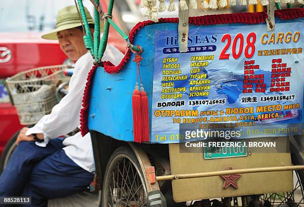 Pedicab driver awaits customers from his vehicle, adorned with Russian advertising in Cyrillic and Chinese script, in Beijing's Russian trade...