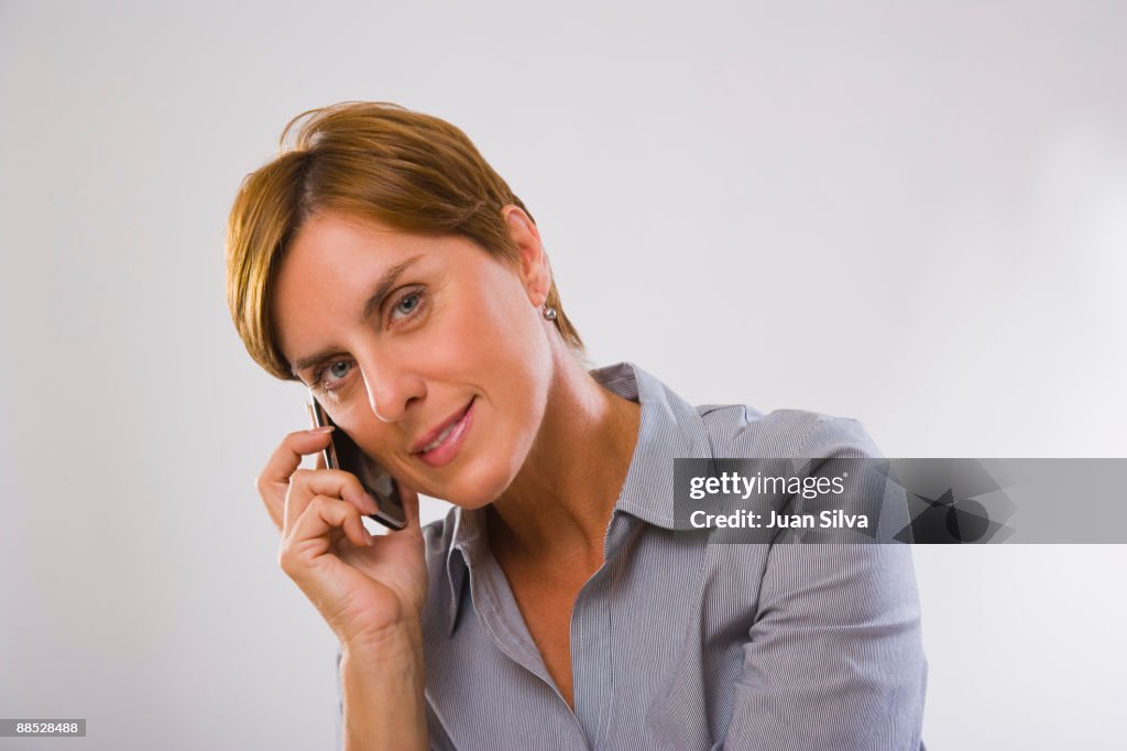 Woman using mobile phone, smiling, portrait