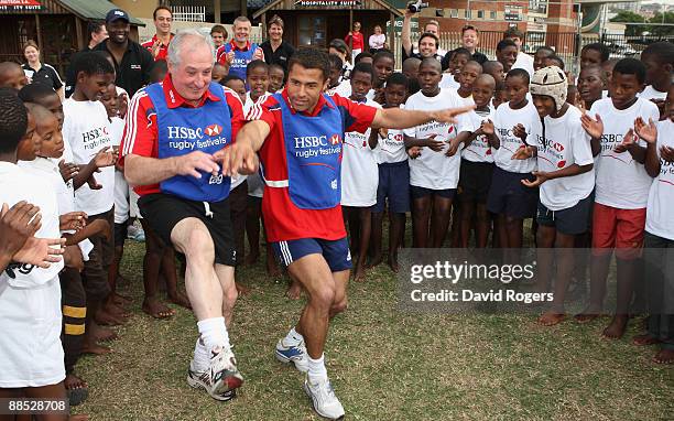 Jason Robinson of British and Irish Lions and former British and Irish Lions player Gareth Edwards dance with children as they sing Shosholoza during...