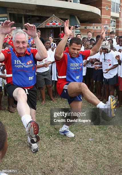 Jason Robinson of British and Irish Lions and former British and Irish Lions player Gareth Edwards dance with children as they sing Shosholoza during...