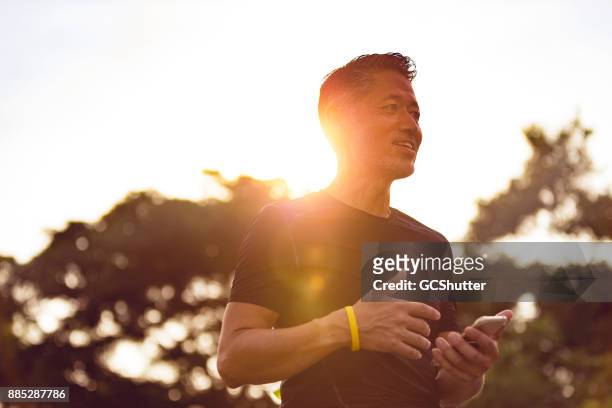 ältere japaner mit seinem smartphone während des sonnenuntergangs - asia ray stock-fotos und bilder