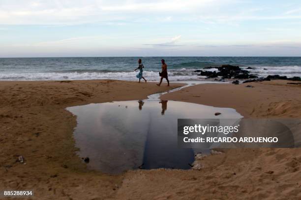 People walk at the beach in the tourist zone of El Condado in San Juan, Puerto Rico on November 28, 2017. / AFP PHOTO / Ricardo ARDUENGO / TO GO WITH...