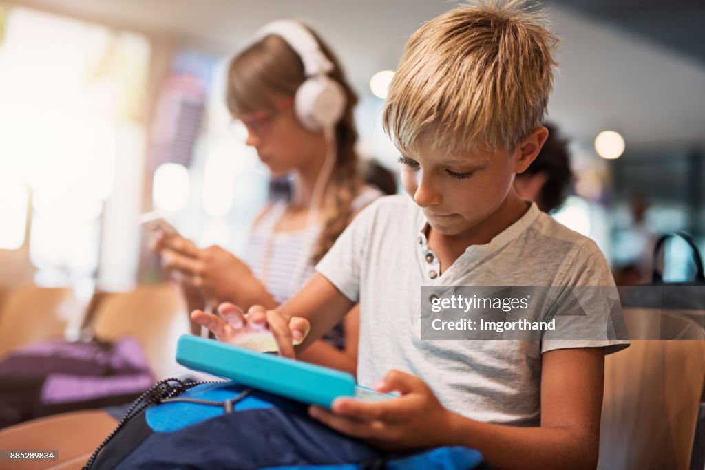 Kinder spielen mit Tabletten während der Wartezeit am Flughafen
