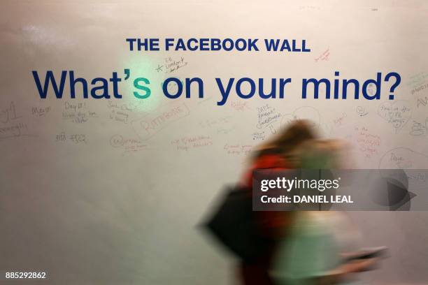 Employees walk past he Facebook Wall at Facebook's new headquarters, designed by Canadian-born American architect Frank Gehry, at Rathbone Place in...