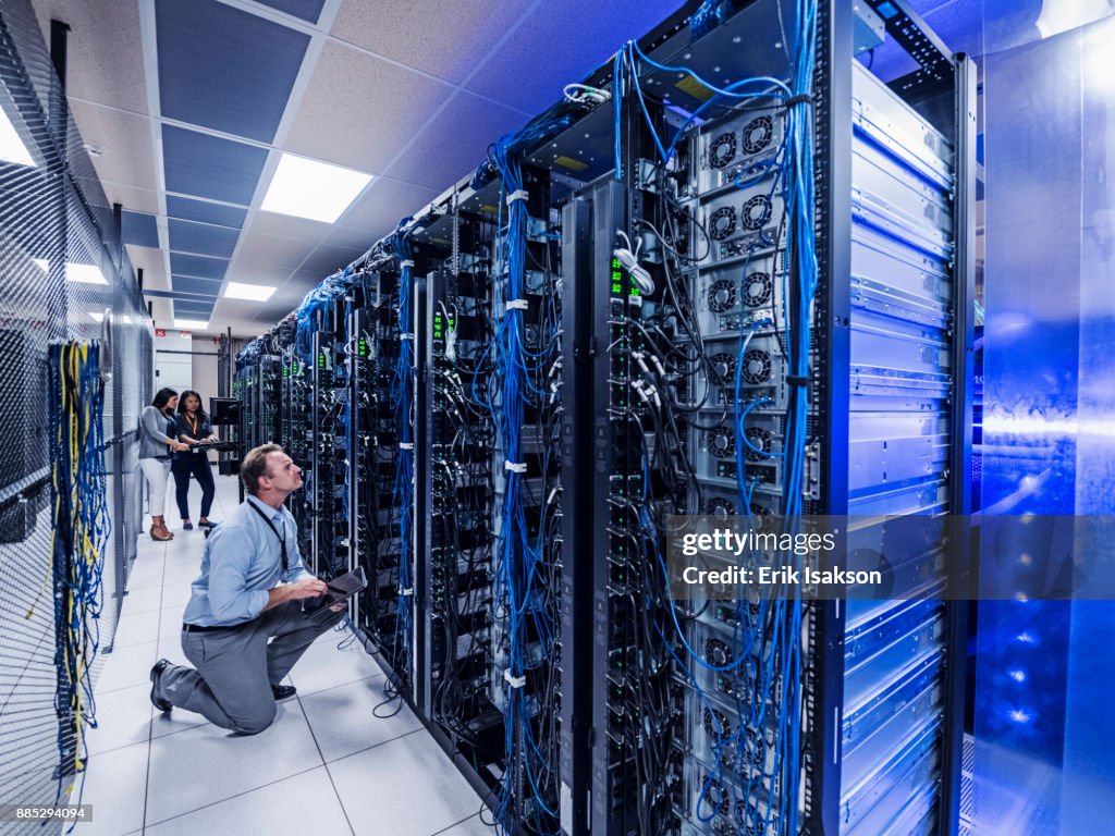 Man and two women working in server room