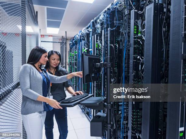 two women working with computer in server room - datacenter fotografías e imágenes de stock