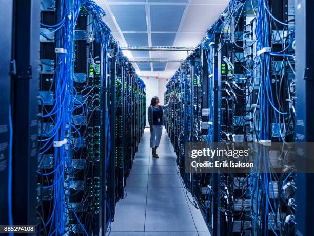 woman standing in aisle of server room - big tech stock pictures, royalty-free photos & images