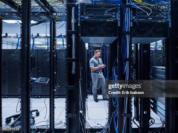 man using mobile phone in server room - netzwerkserver stock-fotos und bilder