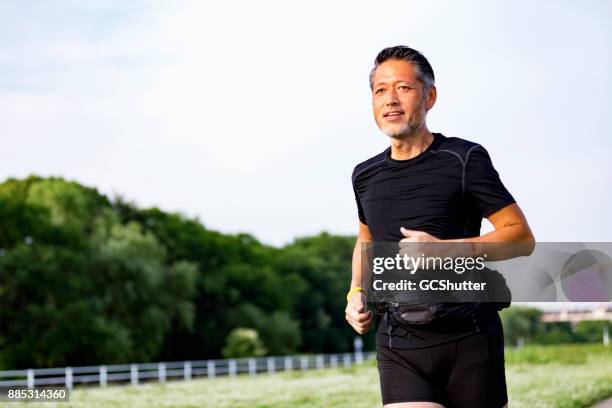 active japanese senior man jogging against the sunshine - male jogging stock pictures, royalty-free photos & images