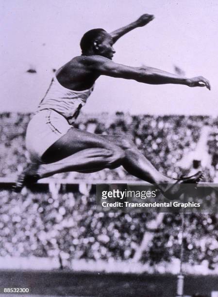 American athlete and Olympic gold medal winner Jesse Owens in midair as he completes in the Long Jump at the Olympic Games, Berlin, Germany, early...