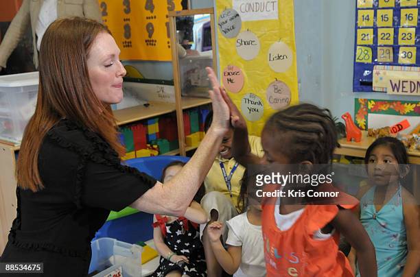 Julianne Moore, Artist Ambassador for Save the Children's U.S. Programs, gives a high five to a young school girl after the "Disaster Decade: Lessons...