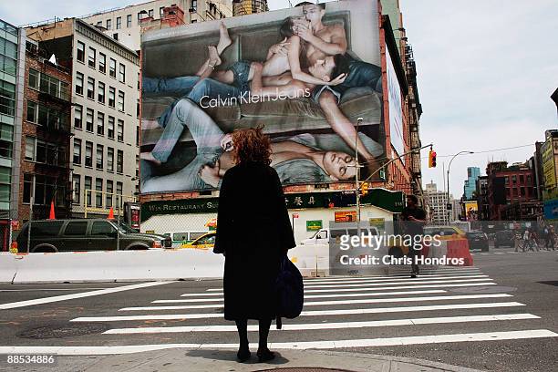 Woman stands by a crosswalk near a Calvin Klein billboard on the side of a building June 17, 2009 in the SoHo neighborhood of New York City. The...