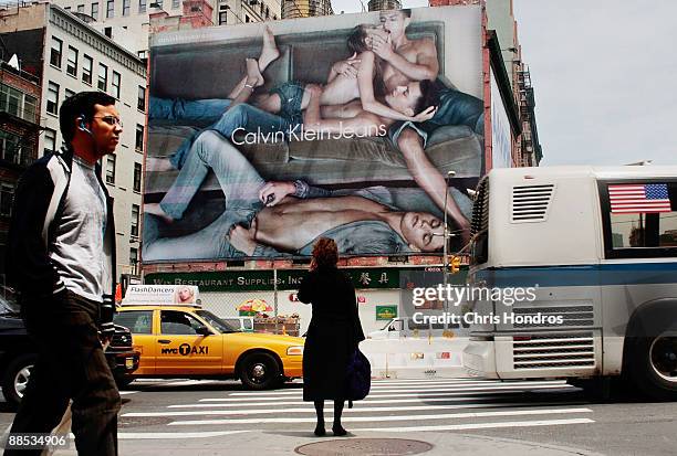 Pedestrians stand on a sidewalk near a Calvin Klein billboard on the side of a building June 17, 2009 in the SoHo neighborhood of New York City. The...
