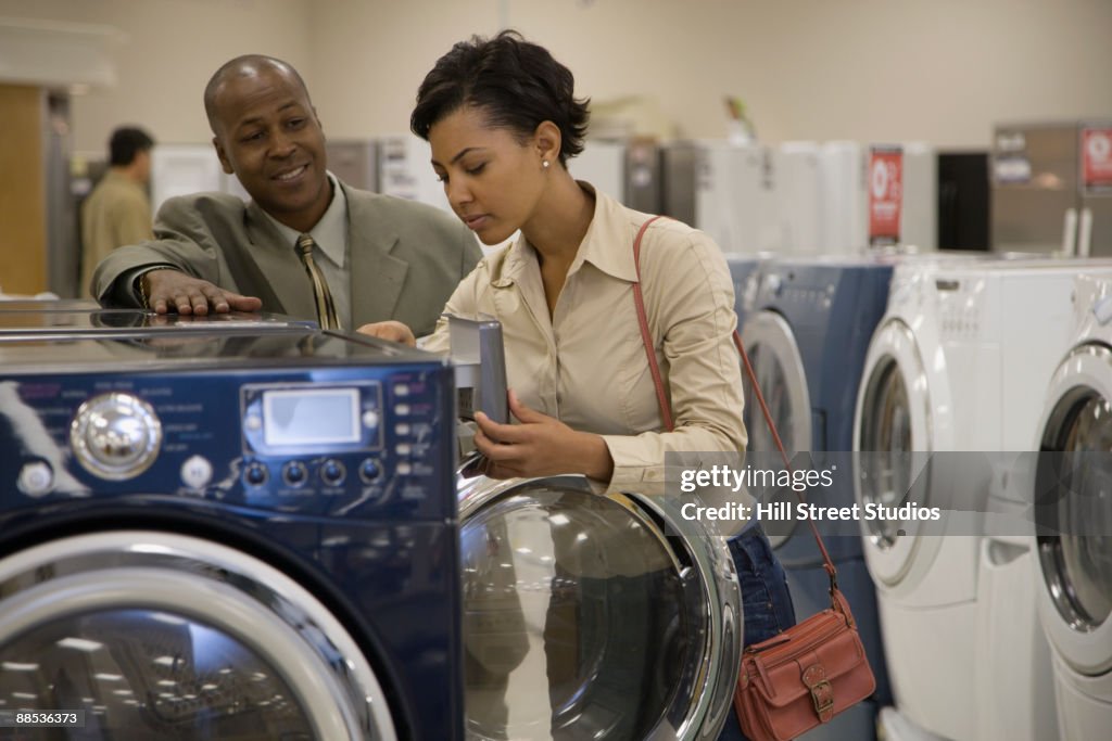Salesman showing customer washing machine in showroom