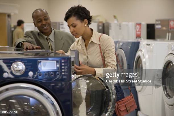 salesman showing customer washing machine in showroom - buying washing machine stock pictures, royalty-free photos & images