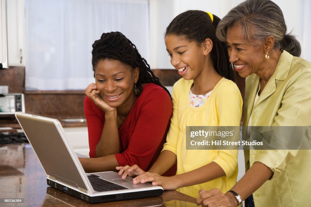 African girl showing mother and grandmother how to use laptop