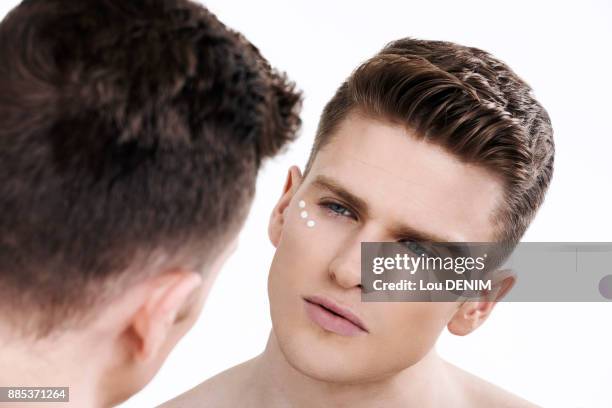 topless man, looking in the mirror, eye creame on his face, little dots of cream around the eye - man eye cream stock pictures, royalty-free photos & images