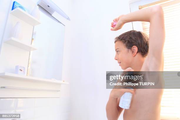 france, young boy in the bathroom using spray. - boy armpit stock-fotos und bilder