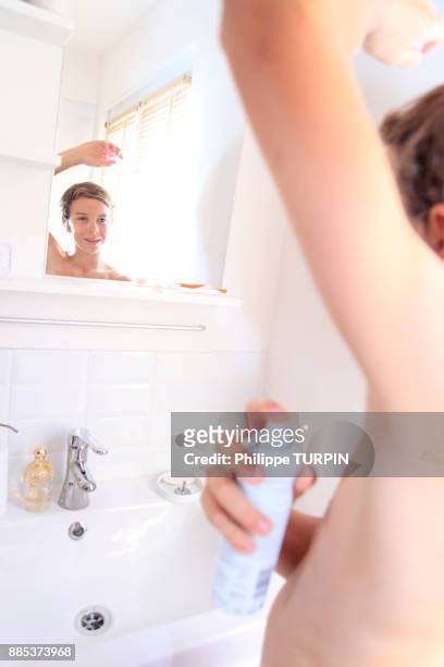 france, young boy in the bathroom using spray. - boy armpit stock-fotos und bilder